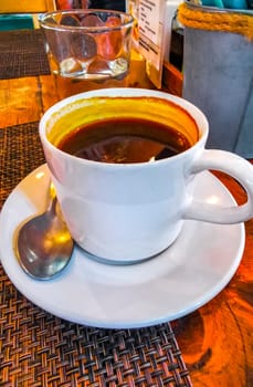 Glass cup of americano black coffee with spoon plate and glass of water on table food and drink in the restaurant cafe in Playa del Carmen Quintana Roo Mexico.