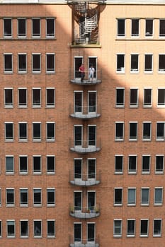 Vertical view of two men standing on the balcony of a brick-built building in Hamburg, Germany