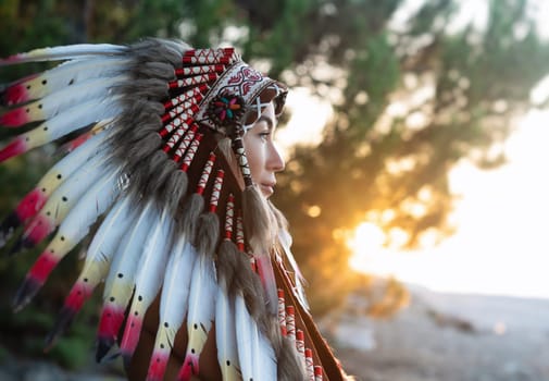 Portrait of a girl with hands in Native American headdresses in nature in the sunset light