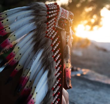 Portrait of a girl with hands in Native American headdresses in nature in the sunset light