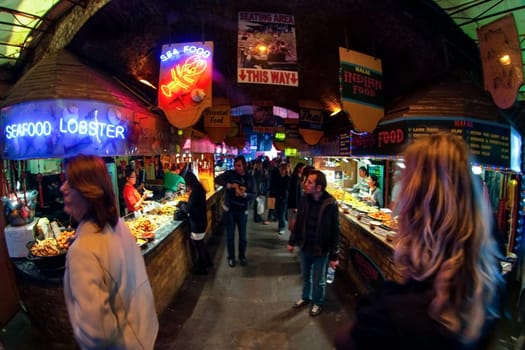 London, United Kingdom - April 01, 2007: Unknown shoppers walking near street food stalls at Camden Lock, famous market at UK capital. Extreme wide perspective (fisheye) photo