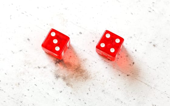 Two red craps dices showing Natural or Seven Out (number 3 and 4) overhead shot on white board