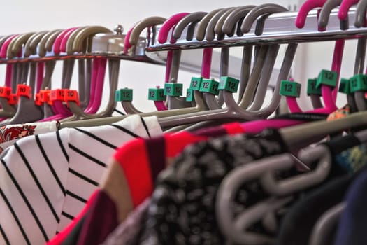 Close up on hangers with various women clothing in charity thrift shop