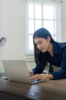 Professional businesswoman working at her home via laptop, young female manager using computer laptop while sitting on desk, work process concept.