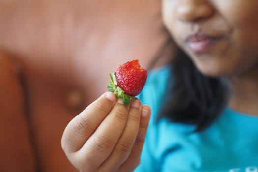 child eating Strawberries sitting on sofa .