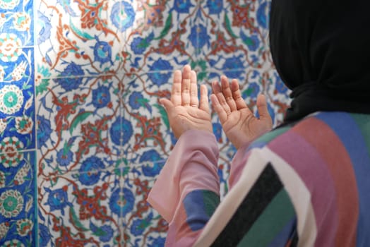 Muslim young woman in hijab is praying in mosque