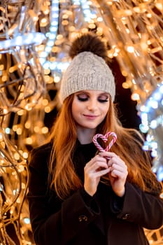 Christmas mood. Woman with long hair in sity decorated for Christmas. She is dressed in a black coat