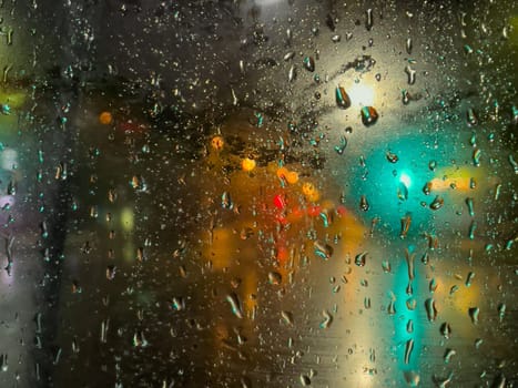 Rain bokeh road lights. Abstract shot of evening city traffic bokeh. Multicolored lights of the evening city and passing cars through a wet rainy window