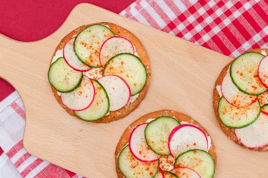 Light Breakfast or Diet Eating - Crispy Cracker Sandwich with Cream Cheese, Fresh Cucumber and Radish on Wooden Cooking Board on Magenta Background