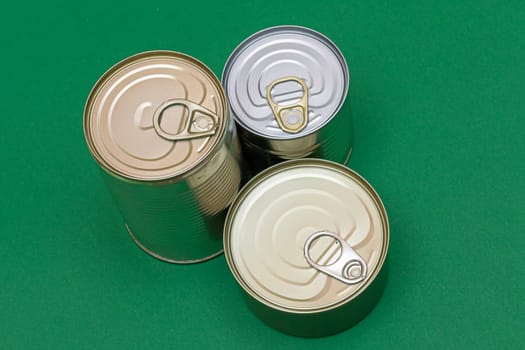 A Group of Stacked Tin Cans with Blank Edges on Green Background. Canned Food. Different Aluminum Cans for Safe and Long Term Storage of Food. Steel Sealed Food Storage Containers