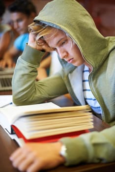 Classroom, students and high school boy with books, knowledge and studying for development at academy. Teenager, reading and learning process with thinking, scholarship and education for assessment.