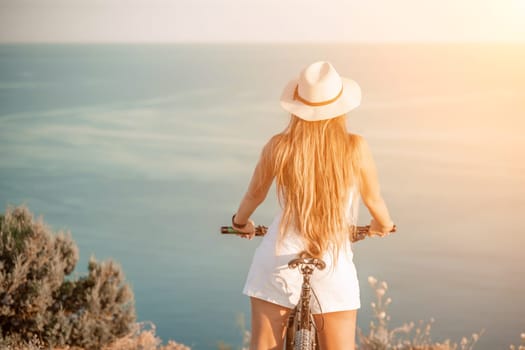 Woman travel bike sea. Happy woman cyclist sitting on her bike, enjoying the beautiful mountain and sea landscape, signifying the idea of an adventurous bike ride