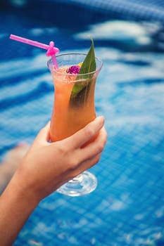 A woman in the pool drinks a cocktail. Selective focus. Kid.