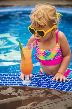 A child in the pool drinks a cocktail. Selective focus. Kid.