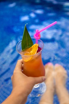 A woman in the pool drinks a cocktail. Selective focus. Travel.