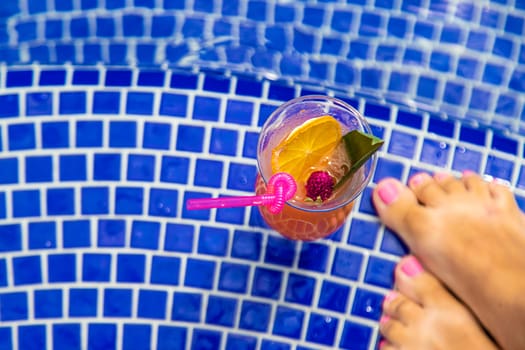 A woman in the pool drinks a cocktail. Selective focus. Travel.