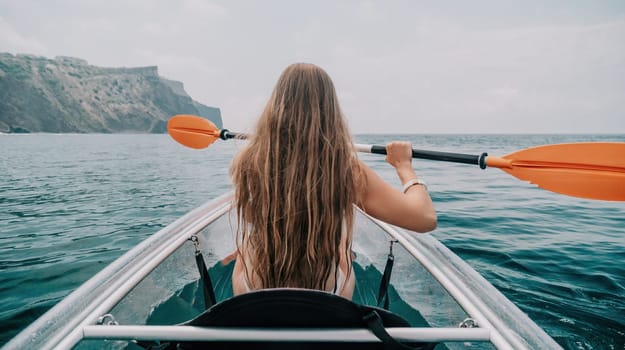 Woman in kayak back view. Happy young woman with long hair floating in transparent kayak on the crystal clear sea. Summer holiday vacation and cheerful female people having fun on the boat.