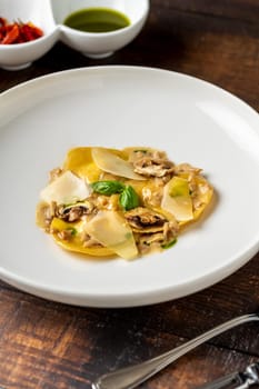 Italian dish ravioli with mushrooms and parmesan on wooden table