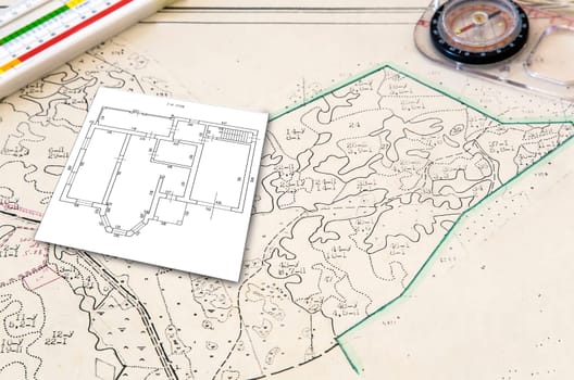 House design and plan of the land plot on the map. Near lie tools: compass, ruler.