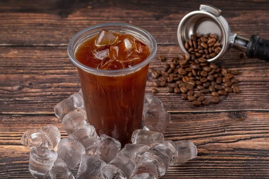 A cup of Iced Americano Coffee with ice cubes placed on a wooden table in a coffee shop. Top view of a glass of coffee.