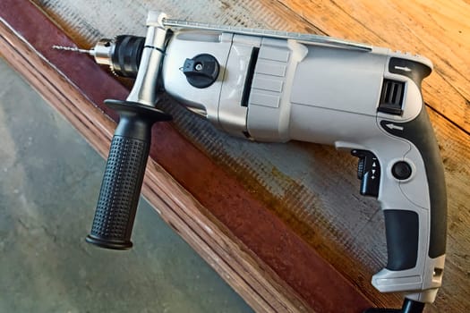 On a carpenter's workbench lies a compact electric hand drill.