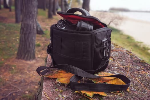 On the background of autumn Park by the river bag with camera and accessories for the photo shoot.