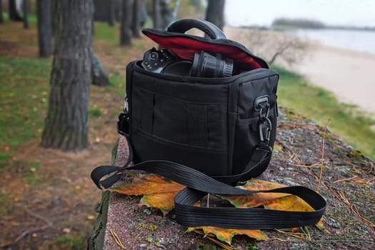 On the background of autumn Park by the river bag with camera and accessories for the photo shoot.