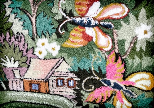 In the wicker part of the canvas you can see a house and a butterfly among the flowers and green leaves.