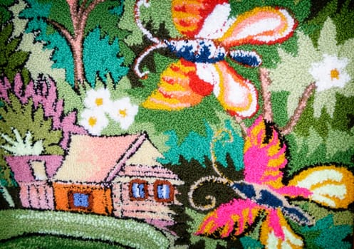 In the wicker part of the canvas you can see a house and a butterfly among the flowers and green leaves.