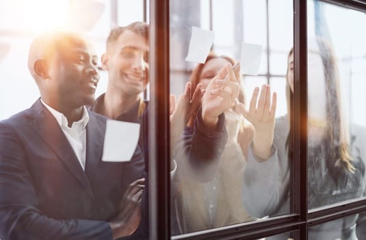 Creative business team looking at sticky notes on glass window