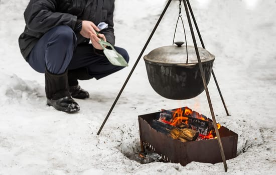 Picnic: winter campfire preparing food under the open sky.