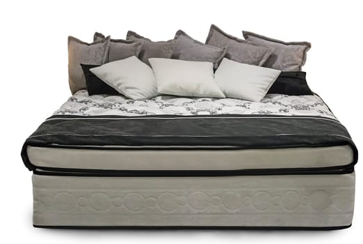 Comfortable double bed with beautiful bedspread and pillows. Presented on a white background.