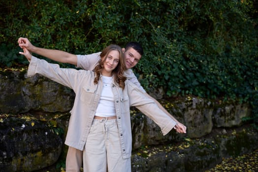 Young Cute Female Hugs Boyfriend. In Autumn Outdoor. Lovers Walking in Park. Attractive Funny Couple. Lovestory in Forest. Man and Woman. Cute Lovers in the Park. Family Concept. Happy Couple.