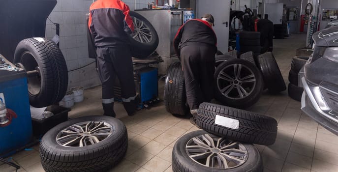 Working inside tire service center. Replacing rubber on car wheels. Wheel balancing. Car tire service center auto repair workshop.