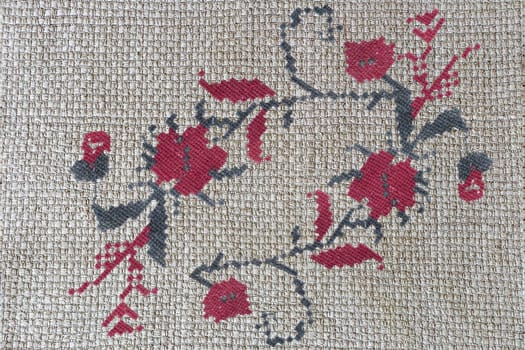 Needlework: embroidered criss-cross pattern of beautiful flowers on canvas. Handmade.