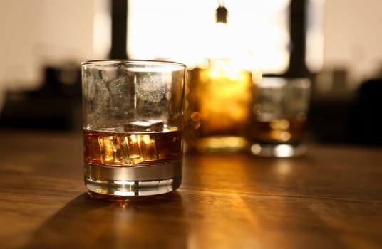 Fingerprint on glass with whiskey stands wooden oak table background. Alcohol addiction concept