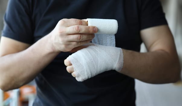 Male hand with tight elastic bandage on arm closeup. Self help sprain concept