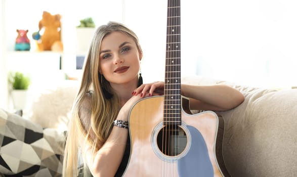 Female Guitar Player Musical Performer Portrait. Attractive Caucasian Woman Holding Instrument. Young Composer Sit on Couch Head and Shoulders Front Shot. Beautiful Musician Girl Looking at Camera