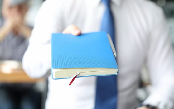 Businessman hold blue diary in hand. Business education concept