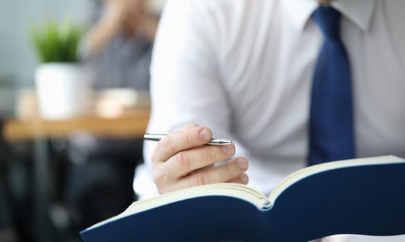 Businessman in white shirt with blueu tie hold diary in hand closeup. Business education concept