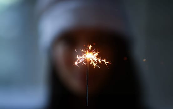 Woman hold sparklers in hand closeup. Xmas dark bacground concept