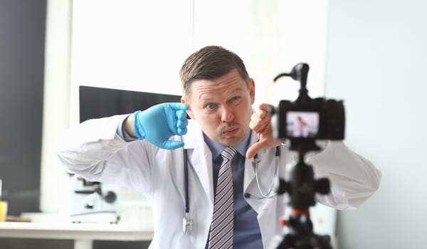 Portrait of funny content maker sitting in front of modern videocamera. Popular blogger talking and showing interesting story to fancy camera. Blogging concept