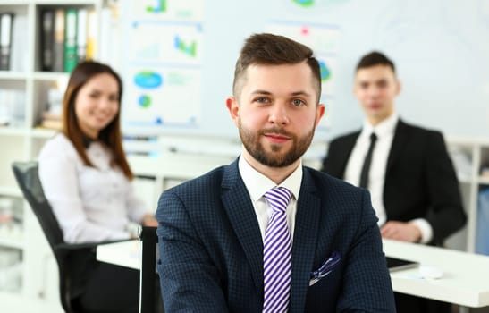 Focus on smart male working in big modern building and discussing important business strategy with younger colleagues and employees. Company meeting concept. Blurred background