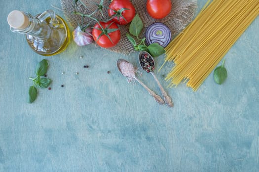 top view of ingredients, spaghetti, red ripe tomatoes, olive oil, green basil, parmesan cheese, onion, garlic and spices. pasta recipe with tomatoes or pasta al pomodoro. flat lay on wooden background with copy space.