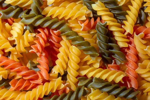 Uncooked Vibrant Colored Fusilli Pasta: A Mesmerizing Culinary Canvas of Multicolored Spirals, Creating a Lively and Textured Background for Gourmet Cooking. Colored Dry Pasta. Raw Macaroni