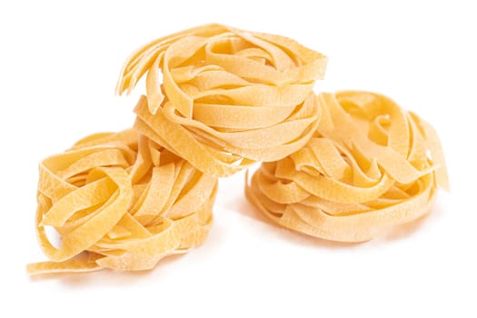 Three Classic Italian Raw Egg Fettuccine - Isolated on White Background. Dry Twisted Uncooked Pasta. Italian Culture and Cuisine. Raw Golden Macaroni Pattern - Isolation