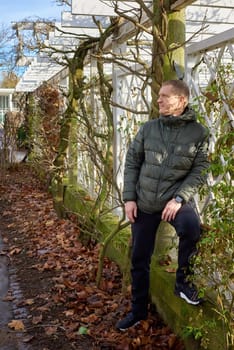 Portrait of handsome man standing outside in autumn weather. Calm Man Outdoors Relaxing And Breathing In Deeply In Autumn Park.