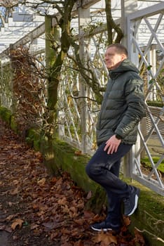 Portrait of handsome man standing outside in autumn weather. Calm Man Outdoors Relaxing And Breathing In Deeply In Autumn Park.