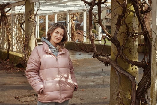 Young beautiful pretty tourist girl in warm hat and coat with backpack walking at cold autumn in Europe city enjoying her travel in Zurich Switzerland. Outdoor portrait of young tourist woman enjoying sightseeing