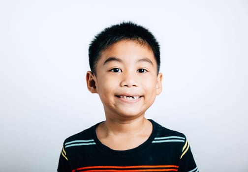 Cheerful schoolboy displays a gap from a lost upper tooth, beaming with joy in isolated portrait on white. Child dental development, tooth fairy moment, and care. teeth new gap dentist problems